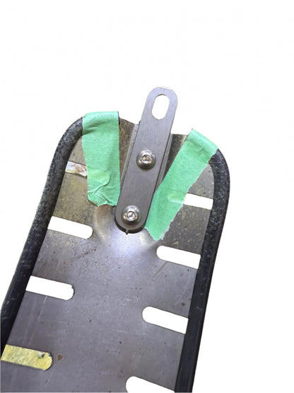 Metal chopper seat pan with green tape on a mechanical background